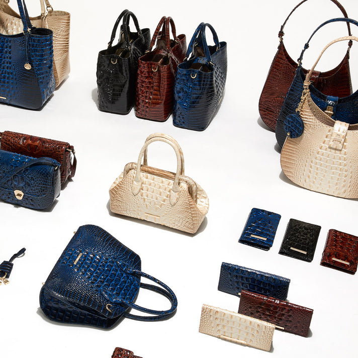 Assorted Brahmin embossed leather handbags, totes, shoulder bags, wallets, and wristlets in ivory, cobalt blue, black, and cognac.