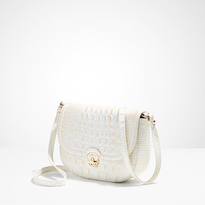 Winter white croc-embossed leather saddle crossbody with flap front, turn-lock closure, adjustable strap, and gold-tone hardware