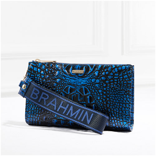 Brahmin blue croc-embossed wristlet with a bold logo webbing strap, photographed against a clean white backdrop.