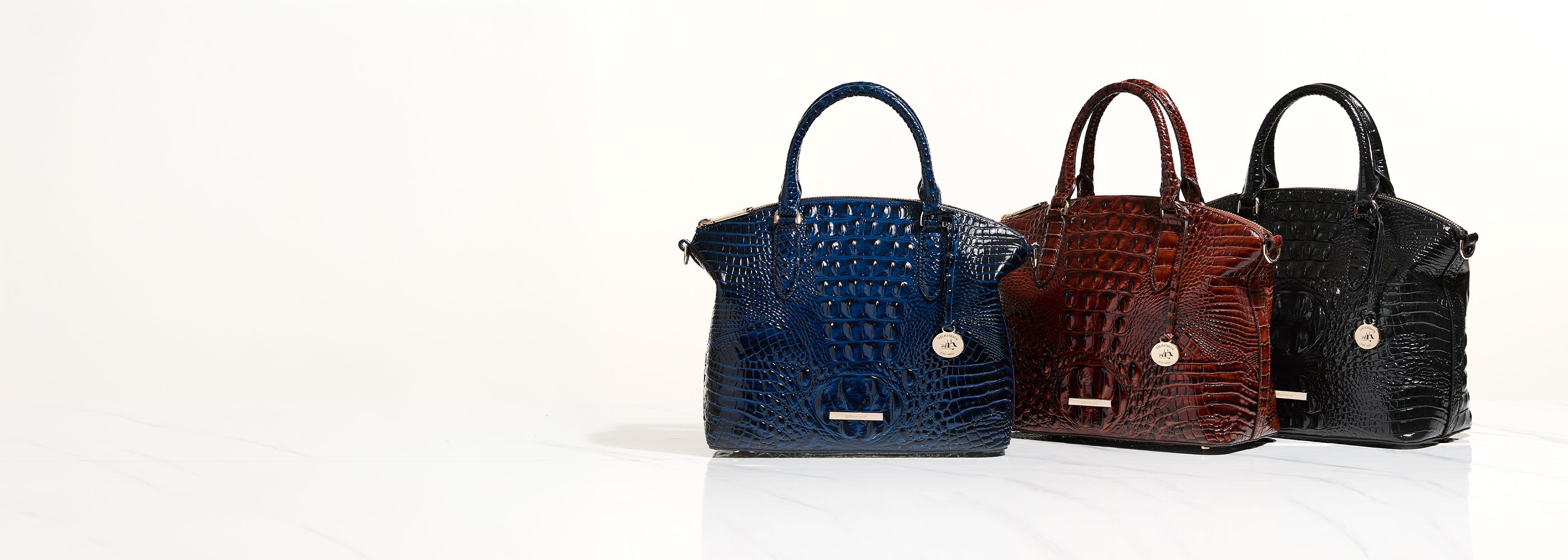Brahmin blue, brown, and black croc embossed leather satchel handbags with top handles, gold hardware, and glossy structured design.