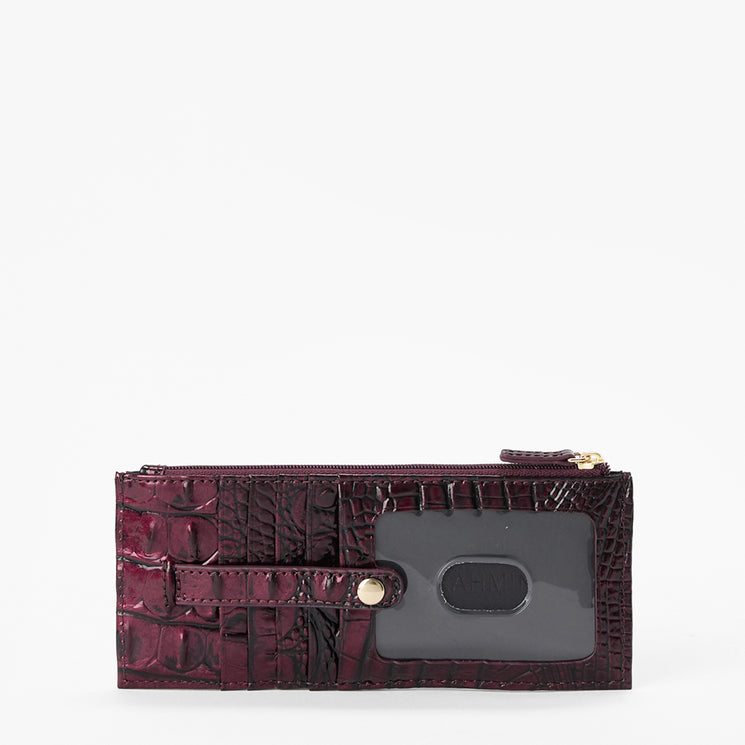 A dark burgundy crocodile-embossed zip-around wallet with a clear ID window and a gold-tone snap button, shown on a plain white background.