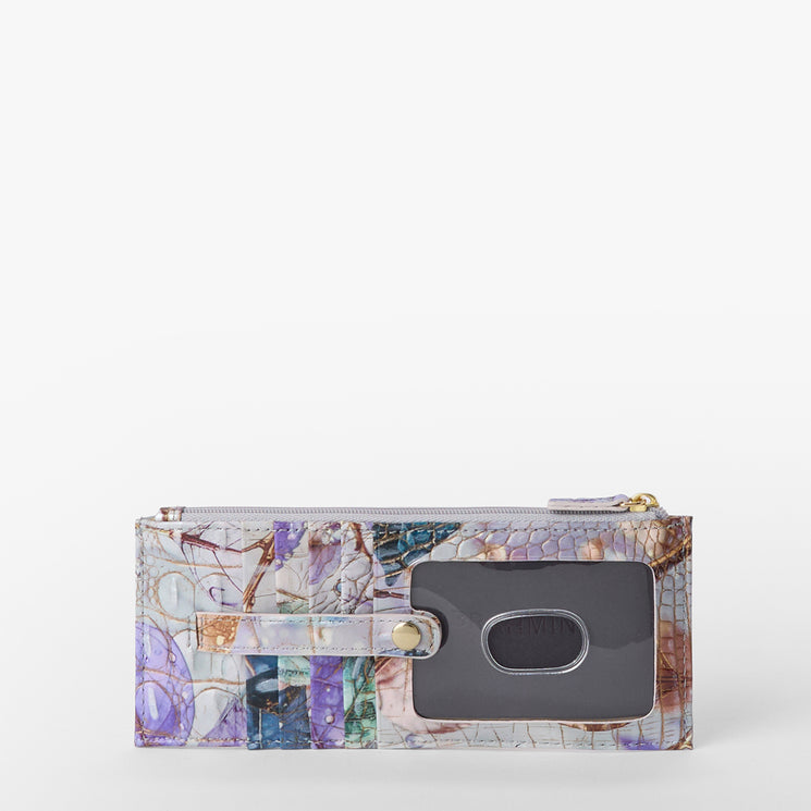 Brahmin textured wallet in a blend of blue, purple, and beige hues with a gold zipper, transparent ID card slot, compact silhouette, and structured shape displayed on a white background.