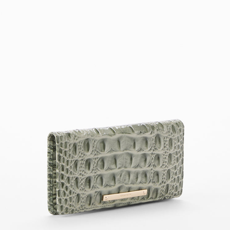 A light sage green crocodile-embossed leather wallet with a gold-tone metal bar clasp, shown on a clean white background.