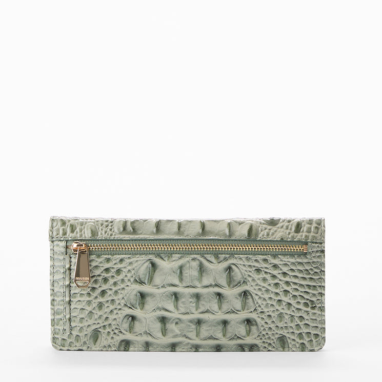 A light sage green crocodile-embossed leather clutch wallet with a gold zipper, shown against a plain white background.