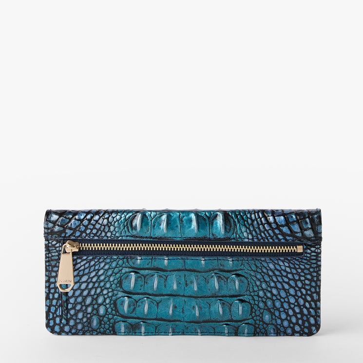 Brahmin rectangular wallet in teal and black with textured embossed pattern, gold-tone zipper hardware, and pull tab, displayed upright on a plain white background. No strap or interior details visible.