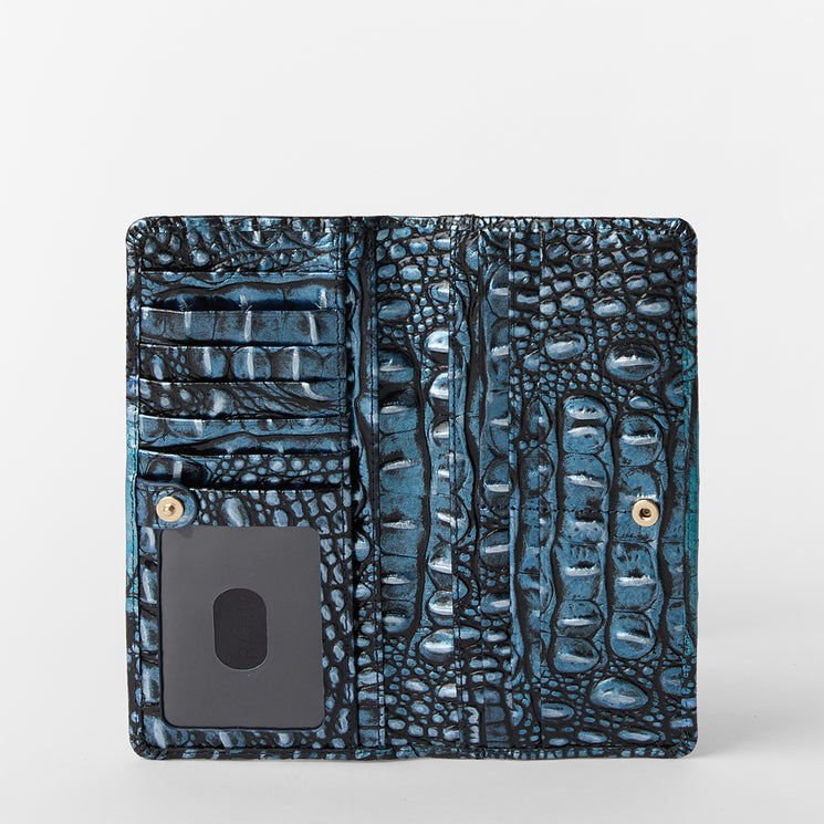 Brahmin blue and black textured bifold wallet open to show multiple card slots, a clear ID window, snap button closures, and detailed embossed patterning, all displayed on a white background.