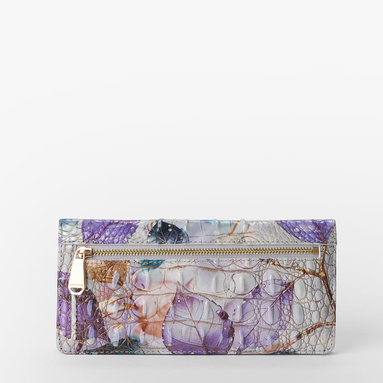 Brahmin rectangular wallet with front zipper pocket, embossed texture in purple, beige, and blue hues, abstract leaf pattern, gold-tone hardware; shown from front with visible silhouette and detailed design.