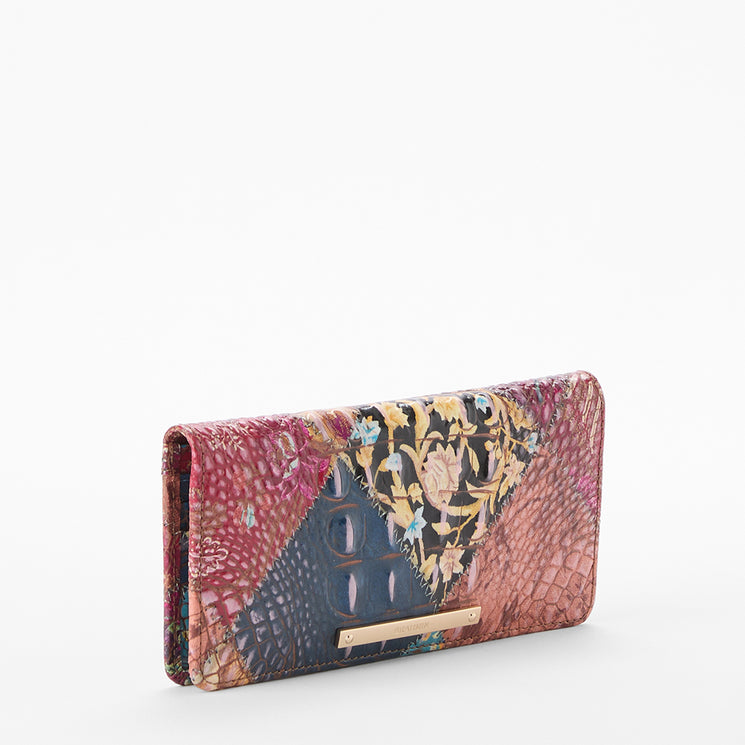 Brahmin rectangular wallet in a vibrant patchwork pattern with multiple textures and floral designs, shown on a plain white background. Features gold-tone hardware and visible stitching detail.