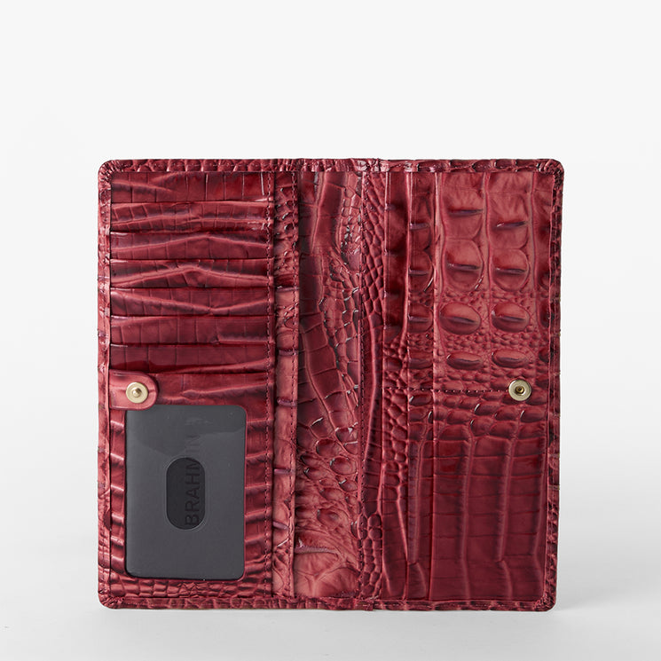 Brahmin red textured leather wallet in a crocodile-embossed pattern, shown open with visible card slots, snap-closure pocket, ID window displaying black card. Compact silhouette with detailed interior organization.