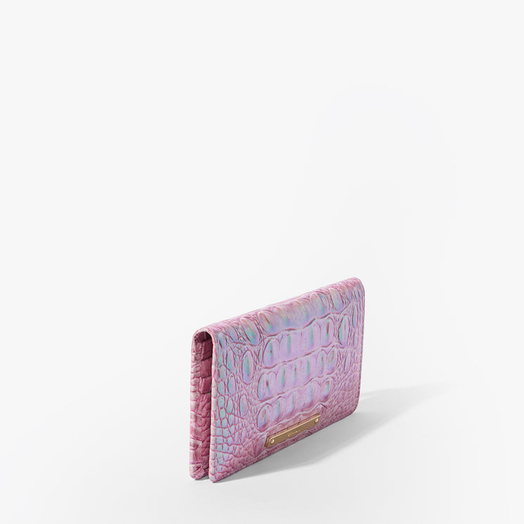 Brahmin Embossed Wallet in pink features a glossy textured finish, upright silhouette, and small metallic logo plate on the front. Set against plain white background. No straps or interior details visible.