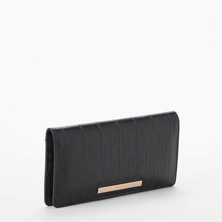 Brahmin black wallet with textured vertical stripes, gold-tone rectangular nameplate on front, structured silhouette, and upright display against a white background. No strap or interior visible.