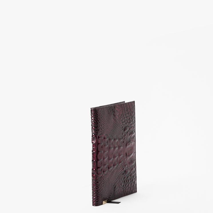 A dark burgundy crocodile-embossed leather notebook or journal standing upright on a plain white background.