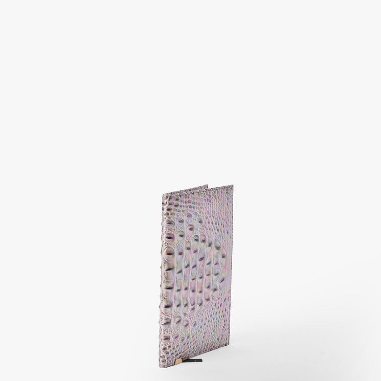 Brahmin pastel notebook with embossed crocodile pattern, slim silhouette, upright on a white background. Cover shows shades of pink, purple, and beige; slightly open to reveal textured design.