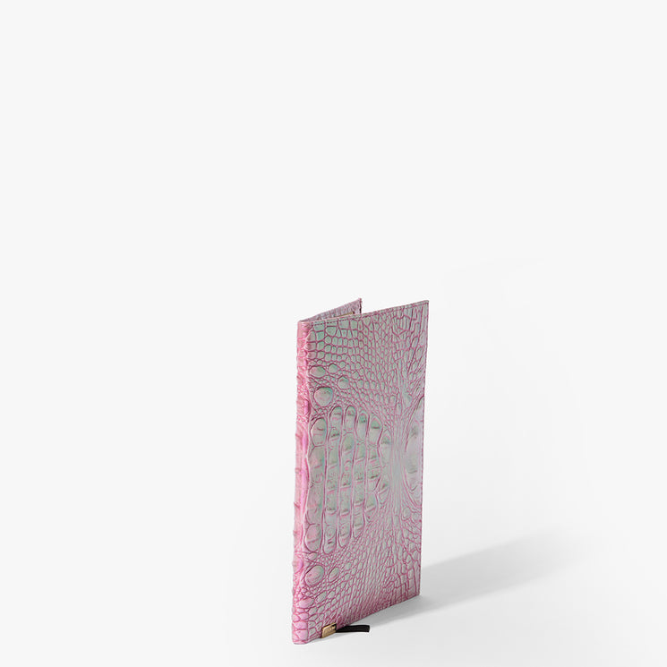 Brahmin pink textured notebook featuring an embossed crocodile pattern, upright on a white background with a black ribbon bookmark visible at the bottom.