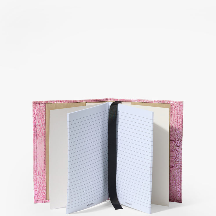 Brahmin pink textured notebook with lined white pages, black ribbon bookmark, and upright silhouette displayed against a plain white background. The cover features an embossed pattern for added detail.
