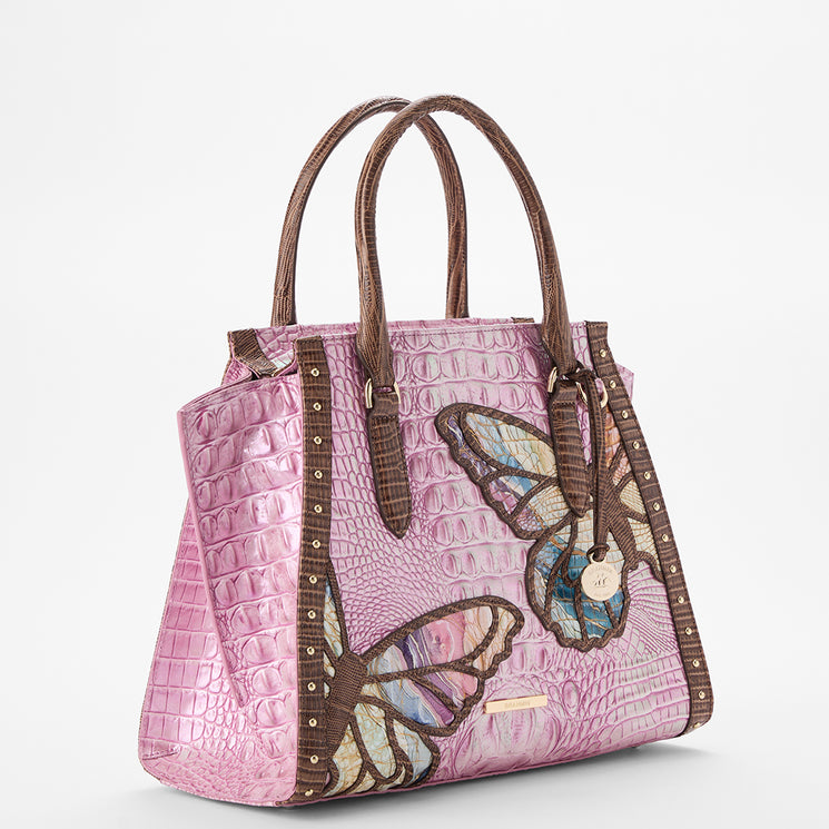 Brahmin pink embossed satchel handbag with brown handles and trim, two oversized butterfly appliqués, gold-tone hardware, and structured silhouette, displayed on a white background.