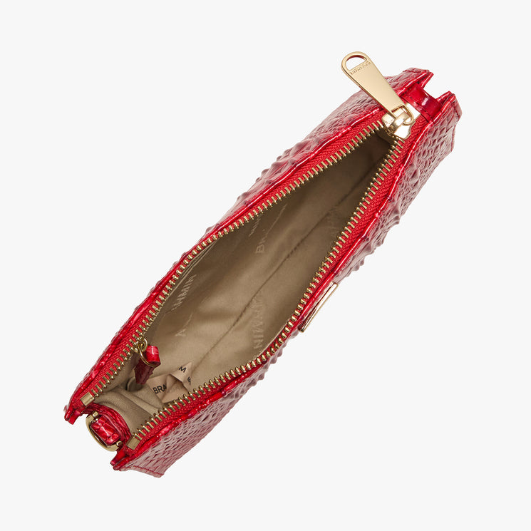 Brahmin red clutch bag with embossed texture and gold zipper, open to reveal a beige interior lining; no visible contents. Top view on white background, showing elegant silhouette and designer details.