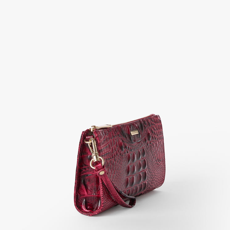 Brahmin clutch in deep red with embossed textured pattern, gold-tone hardware, structured silhouette, detachable wrist strap, and compact shape; set on a plain white background.