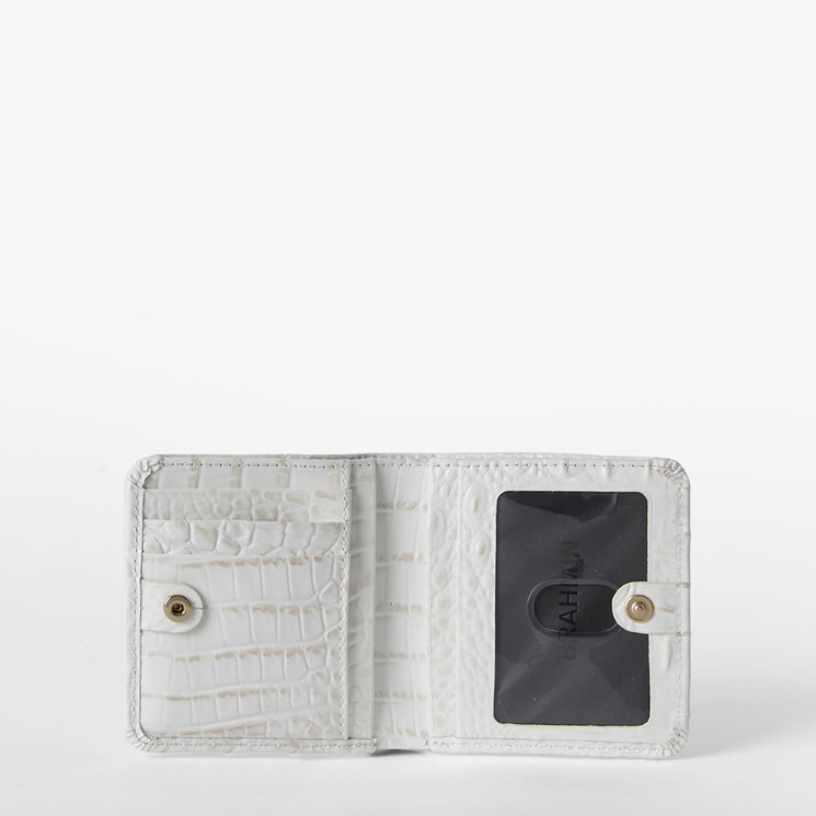 Brahmin white textured wallet with snap closures, open to show left-side card slots and a right-side clear ID window holding a black card. Compact silhouette with embossed pattern, ideal for organizing essentials.
