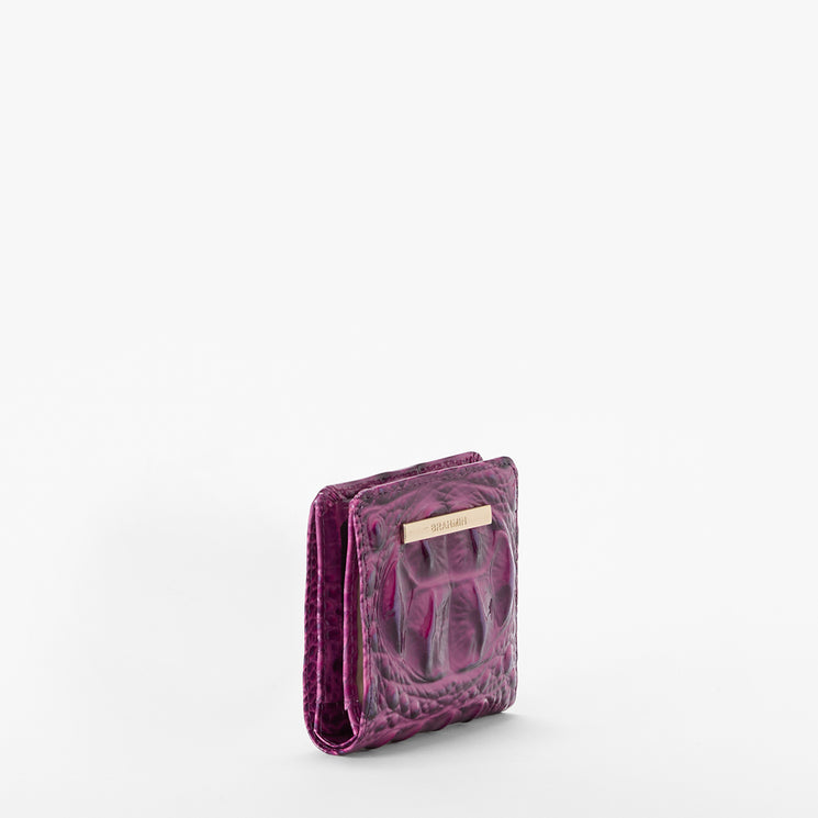 Brahmin small square wallet in textured purple with a shiny finish, featuring a gold logo nameplate on the front. Displayed against a white background; no strap or interior visible in this view.