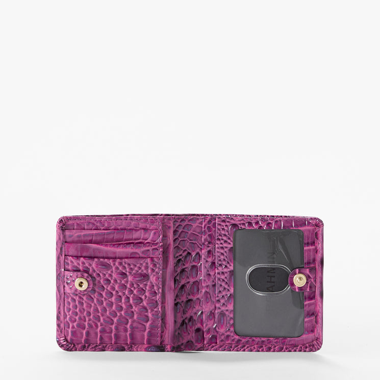 Brahmin purple wallet with textured embossed pattern, gold logo snap buttons, card slots on the left, and a clear ID window on the right. Interior view against a plain white backdrop.