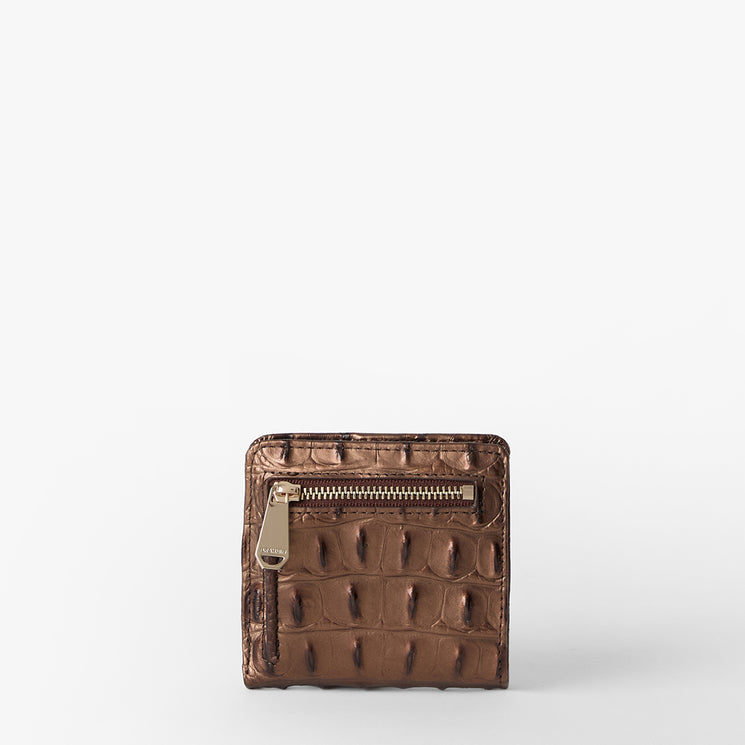 Brahmin zip wallet in brown with embossed textured pattern, gold-tone front zipper pocket, and structured silhouette. Shown against a solid white background. No strap or interior details visible.