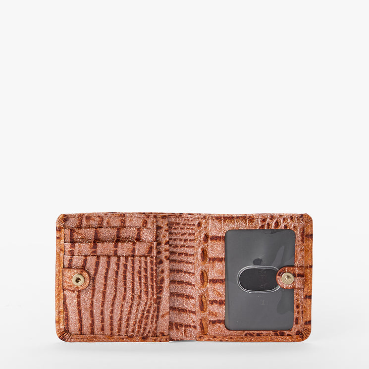 Brahmin brown textured wallet open to show multiple card slots, a small buttoned pocket on the left, clear ID window with metal key ring on the right; classic bifold silhouette shown against white background.