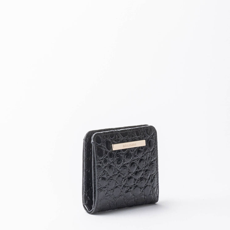 BRAHMIN Jane small black leather wallet with gold-tone nameplate on the front, upright against a white background. Compact silhouette with smooth texture and sleek rectangular shape.
