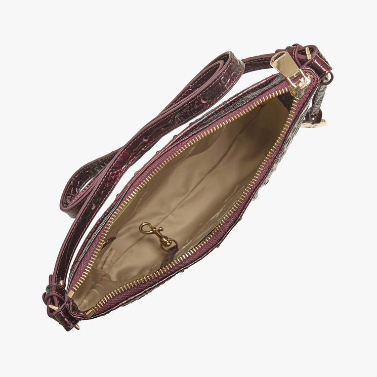 A top-down view of a burgundy textured faux-leather crossbody bag with a gold zipper and a beige interior lining, shown on a light gray background.