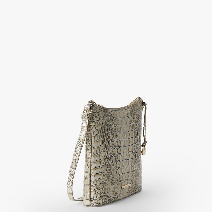 Brahmin small beige crossbody bag with embossed textured pattern, thin adjustable strap, and round gold-tone charm at the strap. Handbag stands upright against plain white backdrop; front and side view shown.