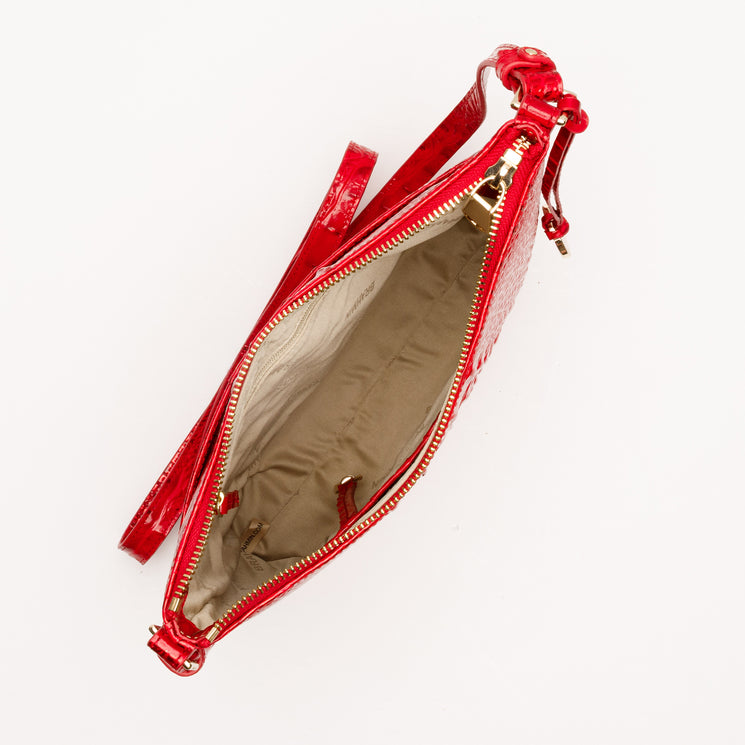 Top-down view of an open red BRAHMIN Katie bag featuring a shiny, textured finish, gold-toned zipper, beige fabric interior, and a matching thin shoulder strap.