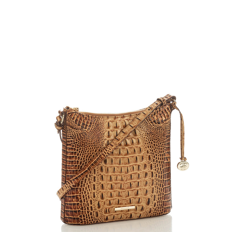 Brahmin brown crossbody bag with embossed textured pattern, gold-tone hardware, zip closure, adjustable strap, and a round gold charm at the zipper. Bag silhouette shown from front; interior not visible.