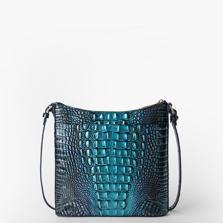 Brahmin rectangular crossbody bag with blue and black embossed texture, slim strap, and top zipper closure, shown on a white background. The silhouette highlights the structured shape and chic hardware detail.