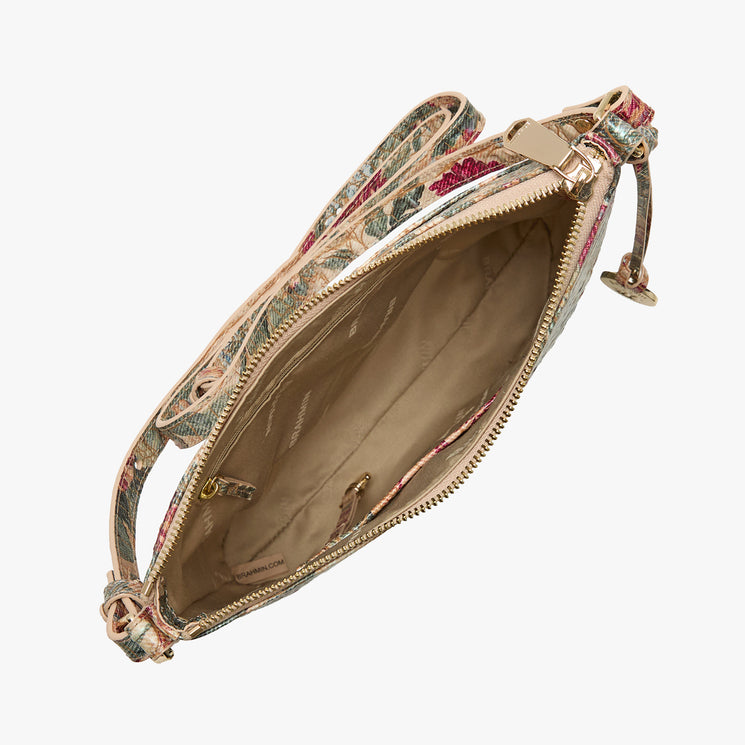 An open crossbody bag with a floral patterned exterior, gold-tone zipper, and beige interior lining, shown on a plain light gray background.