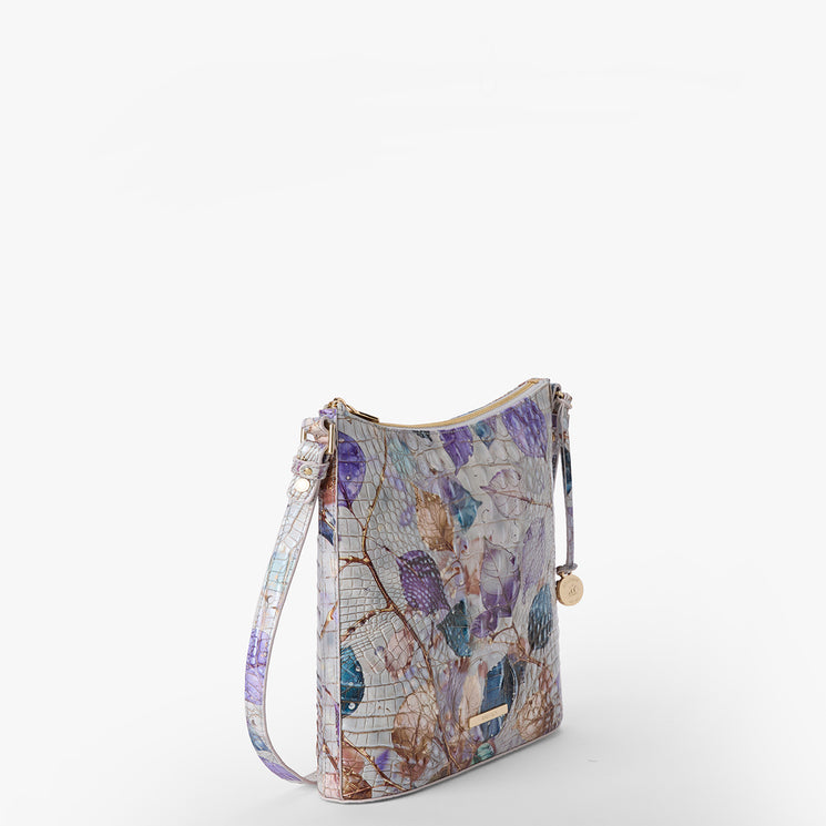 Brahmin pastel floral crossbody bag with gold-tone zipper, adjustable strap, small round gold charm, and structured silhouette. Bag is displayed on a plain white background.
