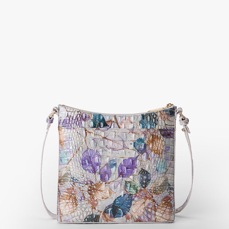 Brahmin crossbody bag with pastel floral pattern over embossed, textured surface, featuring a zipper closure, gold-tone hardware, thin adjustable strap, and compact silhouette.