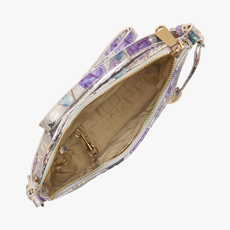Top view of a Brahmin purse featuring a beige interior with gold zipper, internal pocket, and key clip. Exterior shows a pastel purple, blue, and white pattern. Modern silhouette and refined hardware details.