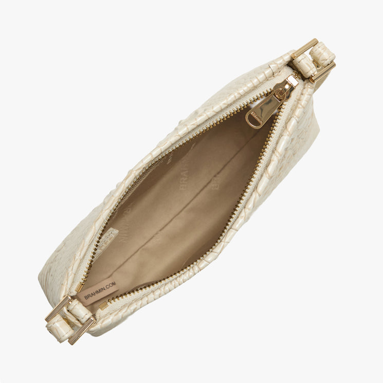 Brahmin beige textured handbag with gold-tone zipper, top view with zipper open. Light tan fabric-lined interior features a small inner pocket. Structured silhouette, no strap visible.