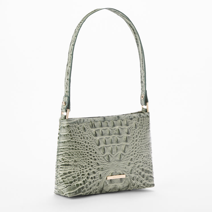 A sage green crocodile-embossed shoulder bag with a single top handle and a small gold-tone metal Brahmin accent on the front, shown against a plain white background.