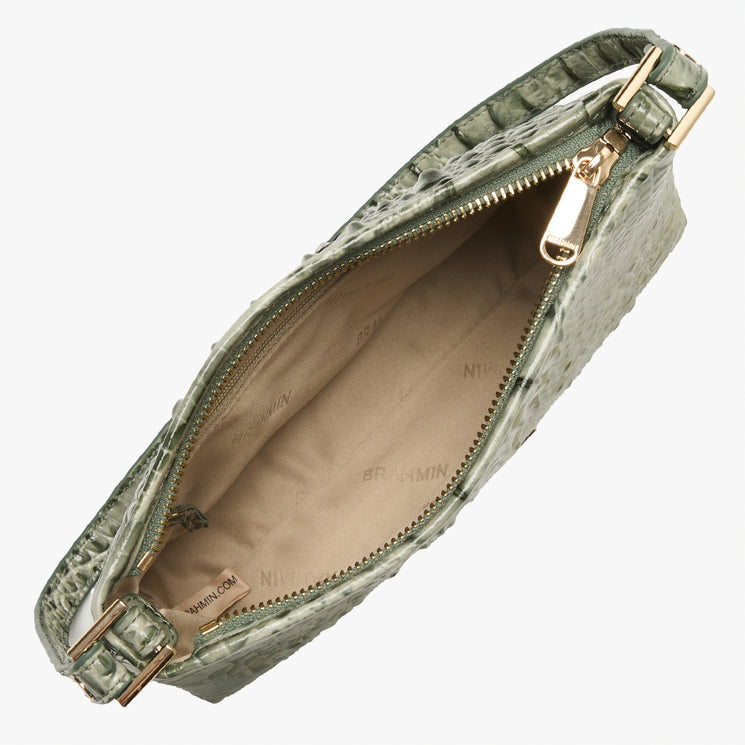 An open green crocodile-embossed handbag with gold-tone hardware and a beige interior lining, shown on a light gray background.