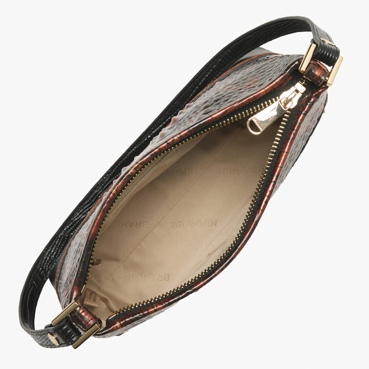 A close-up of a handbag's open interior, showing a brown and black crocodile-embossed exterior, a beige interior lining, and gold-tone hardware.