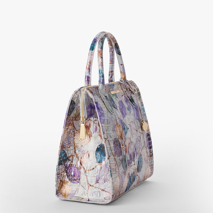 Brahmin structured satchel handbag in a multi-colored floral and textured pattern with gold zipper, double top handles, and smooth silhouette, displayed on a white background.