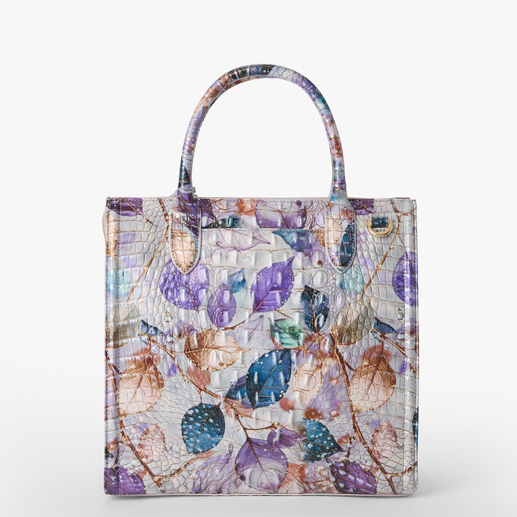 Brahmin structured satchel with embossed texture, colorful purple, blue, and peach leaf pattern, dual top handles, gold-tone hardware, white background; exterior view showing signature design details.
