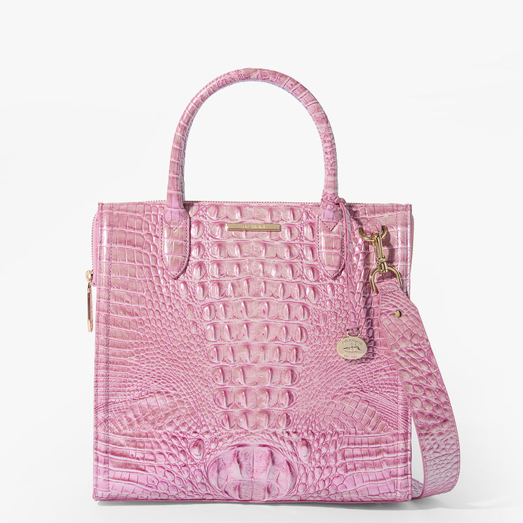 Brahmin pink structured satchel featuring embossed texture, two top handles, gold-tone hardware, front logo plate, hanging charm, and detachable shoulder strap. Bag shown upright on a plain white background.