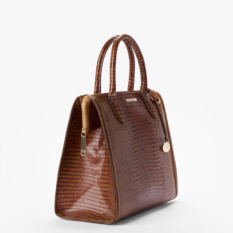 Brahmin brown structured handbag with embossed lizard-skin texture, two top handles, gold-tone zipper closure, and a round gold tag, shown on a white background. Classic satchel silhouette.