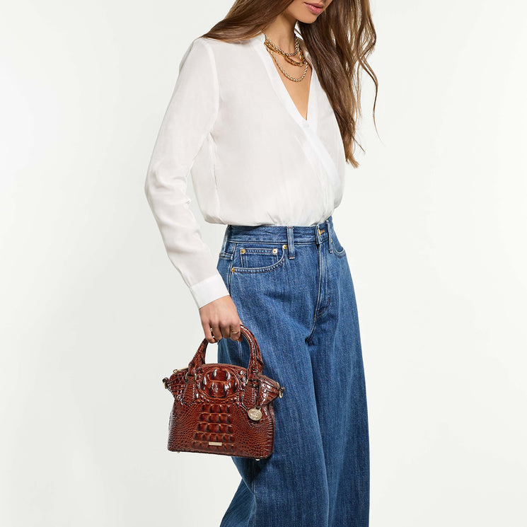 Woman holding Duxie satchel wearing a white blouse and blue jeans on a white background