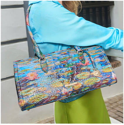Colorful handbag with floral pattern held by a person wearing a blue jacket and green pants.