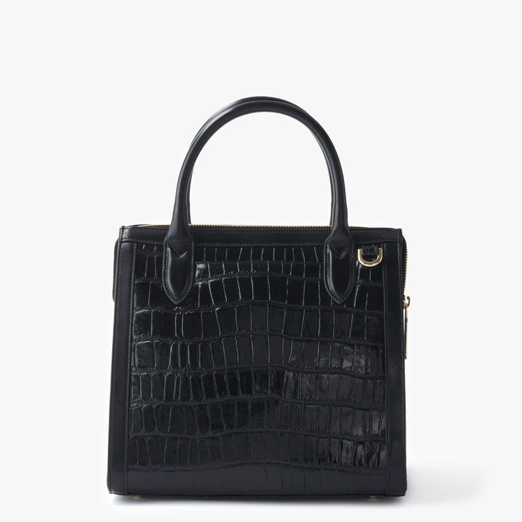 BRAHMIN Small Caroline satchel in black leather with embossed crocodile-inspired pattern, gold-tone hardware, two rounded top handles, zippered closure, and structured silhouette on a plain white background.