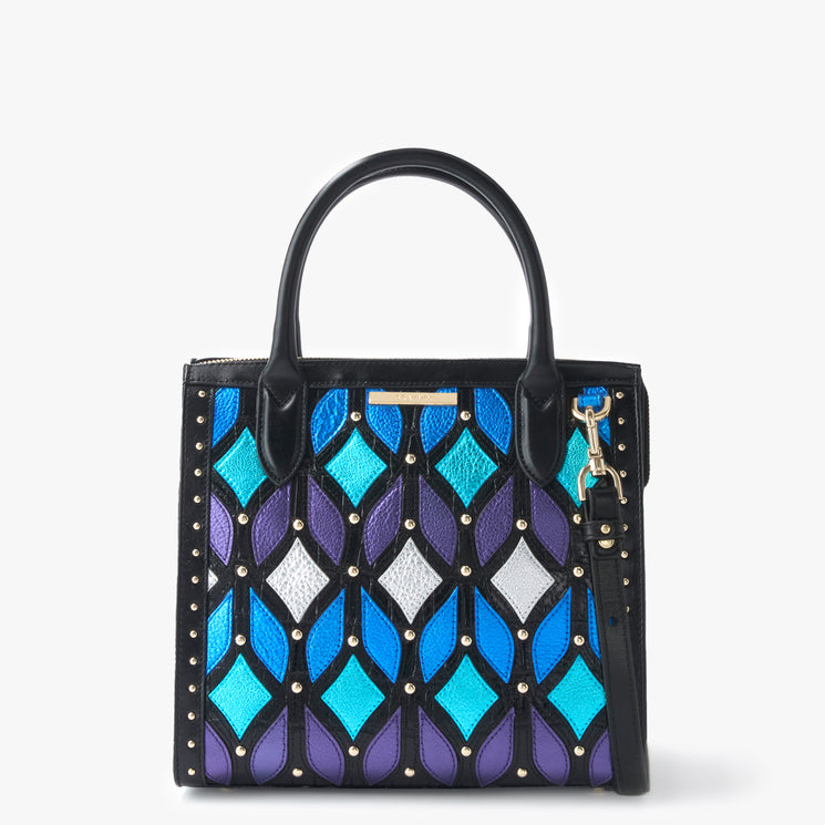 Brahmin Small Caroline satchel in blue, teal, purple, and white geometric pattern with gold-tone studs, short top handles, detachable crossbody strap, flap closure, and structured silhouette; interior visible.