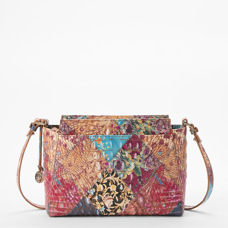 Brahmin patchwork crossbody bag with a multicolor pattern, faux snakeskin-inspired texture, floral accents, gold-tone hardware, adjustable strap, and structured silhouette shown against a plain white background.